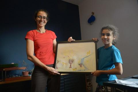 Ao lado da mãe, Danielle Quemel, Ana Beatriz, de 9 anos, exibe um de seus quadros