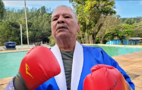 foto do boxeador Maguila vestido com um roupão de luta e luvas de boxe com uma piscina ao fundo